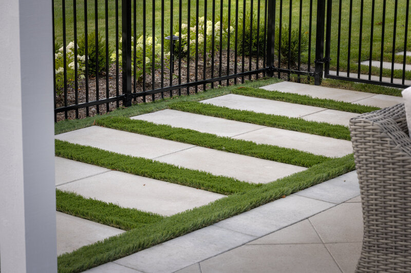closeup shot of an iron fence wit modern slab pathway