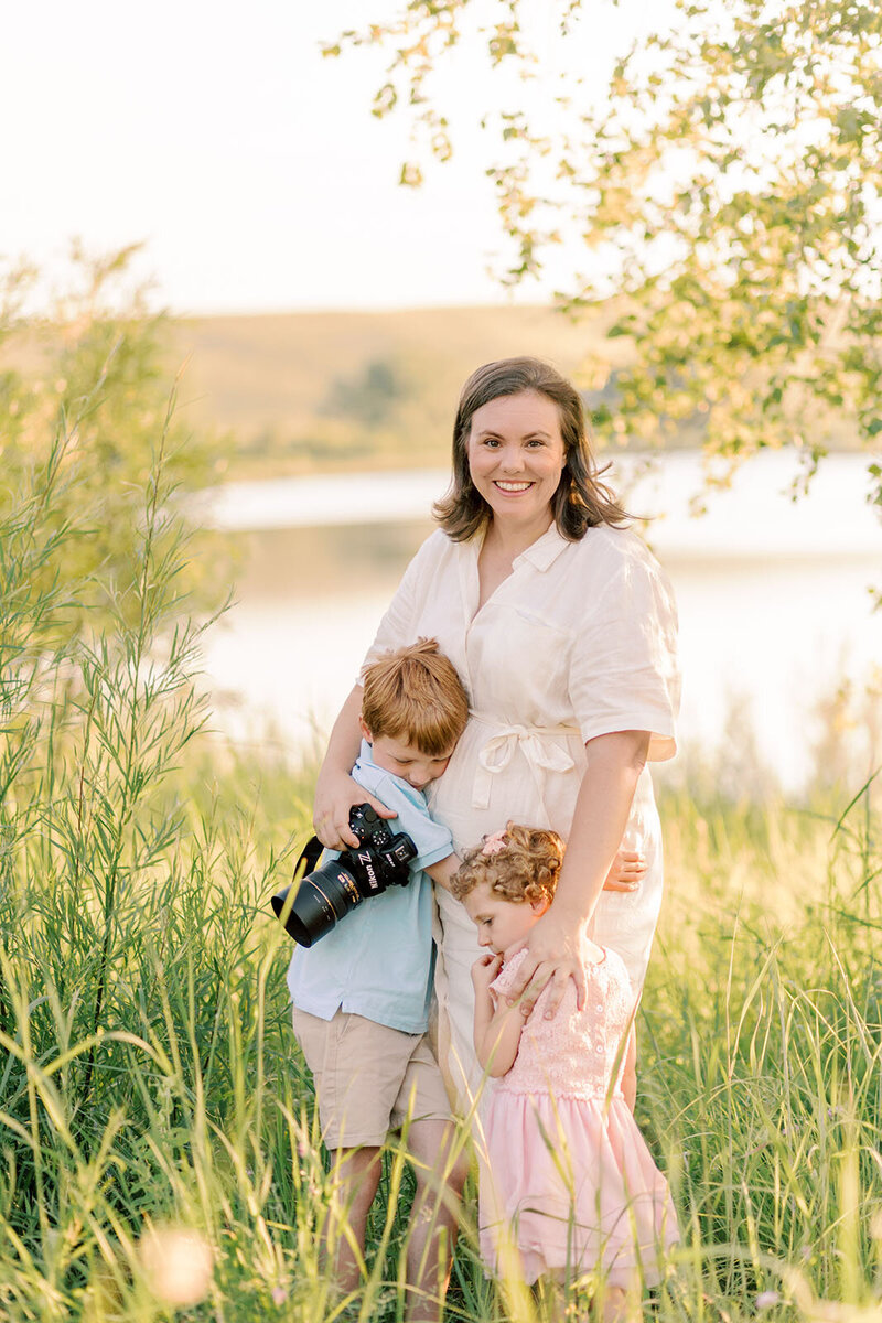 Photographer Kristen Hazelton wearing a purple dress and holding a camera