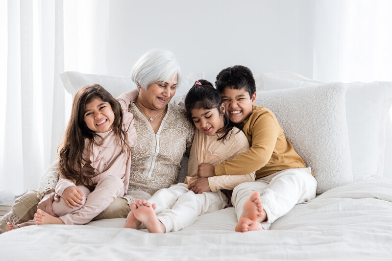 Group of females posed and smiling on a football field in graduation gowns.