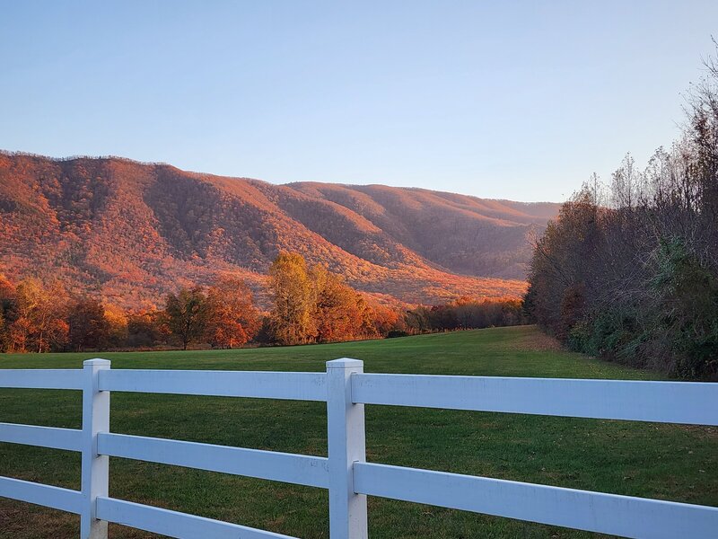 Beautifu fall colored mountain scene with a white picket fence in the foreground at Mountain Shadow Farms' wedding venue