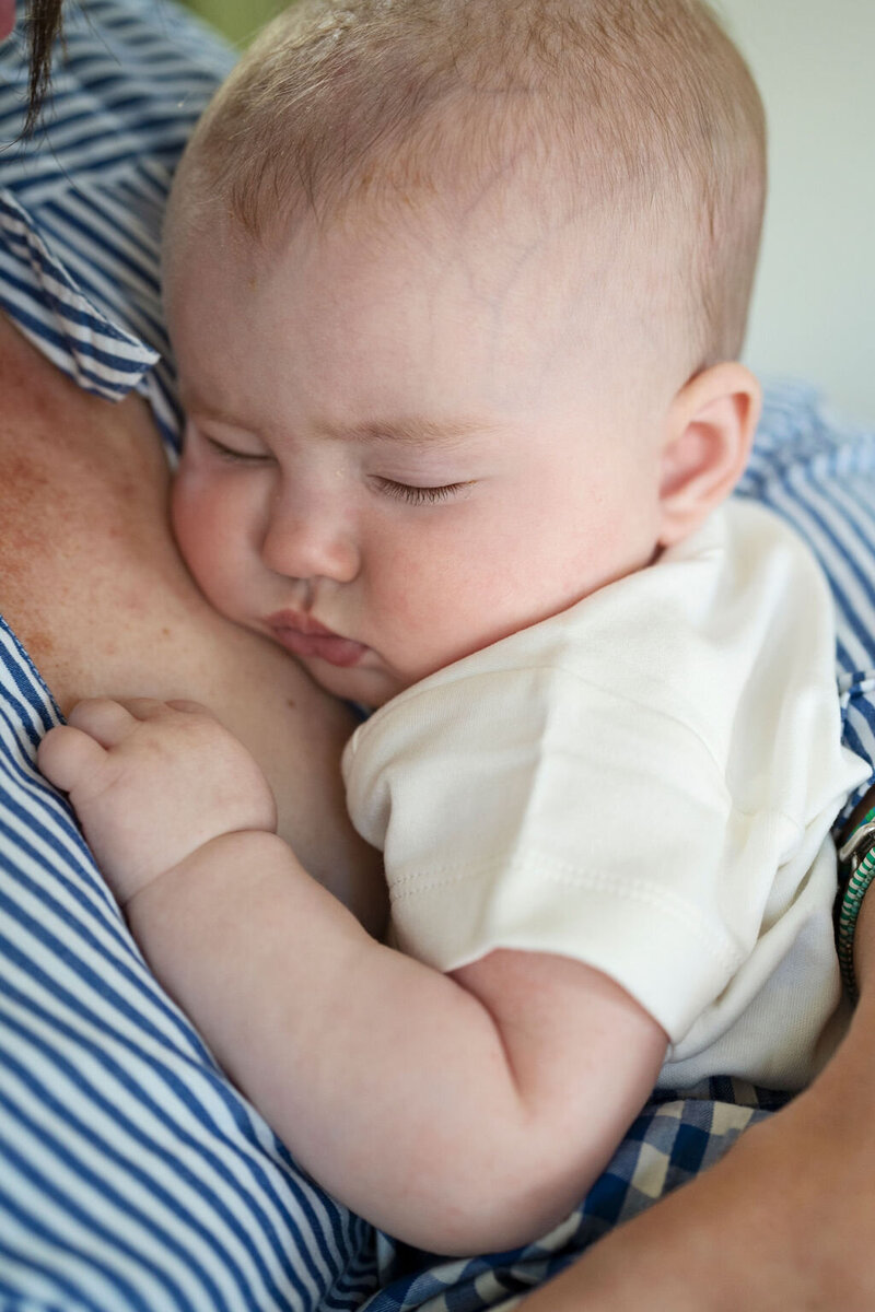 A 5 month old baby girl asleep on her mother's chest