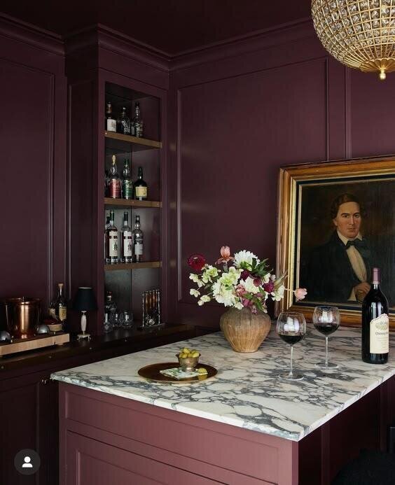 A wine bar featuring a wall adorned with a painting of a man, complemented by rich plum purple hues.