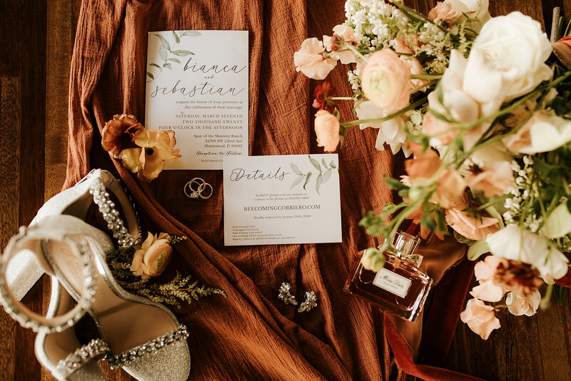 Rings, paper, florals, shoes and perfume flatlay.