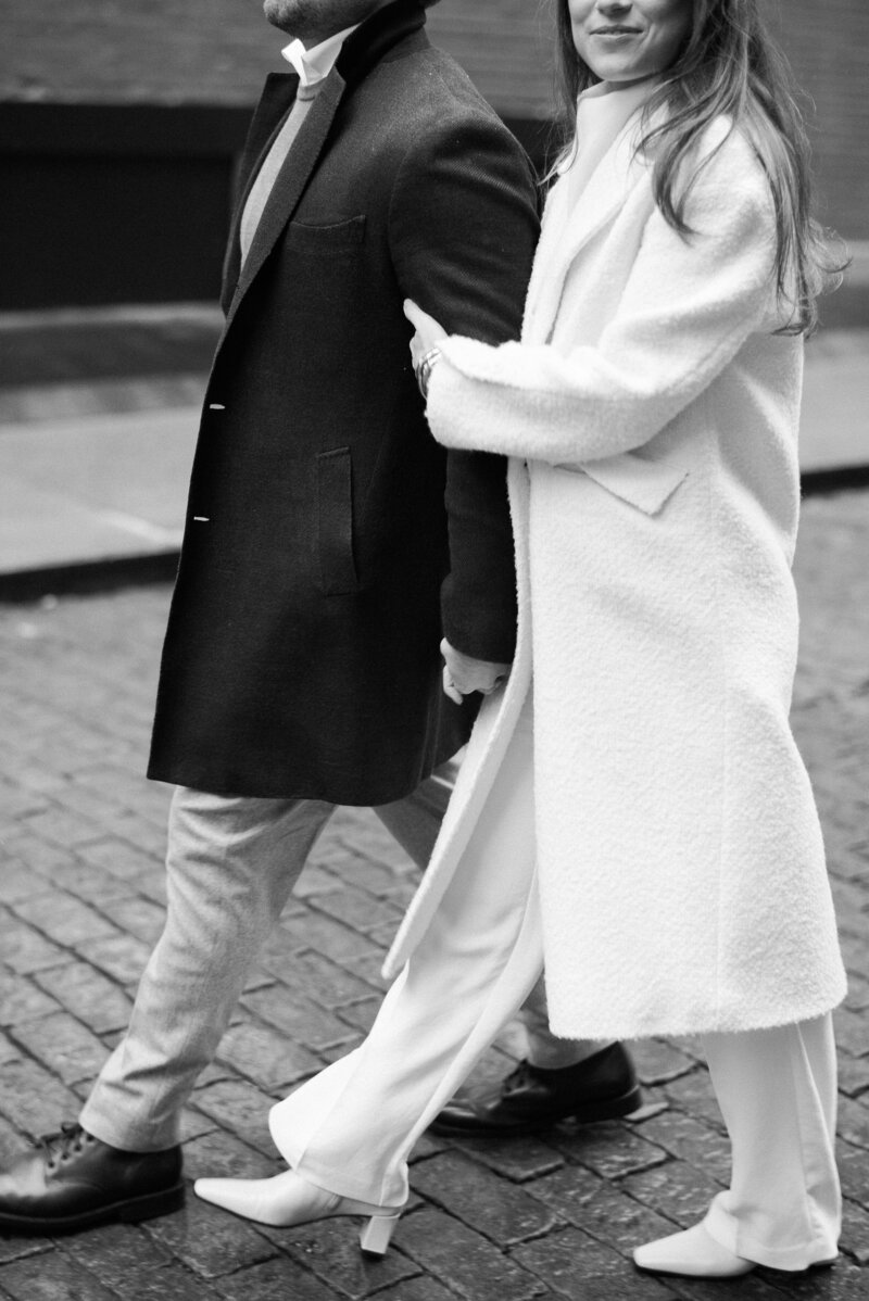 Woman holds her partner's arm while they walk down quiet Soho streets