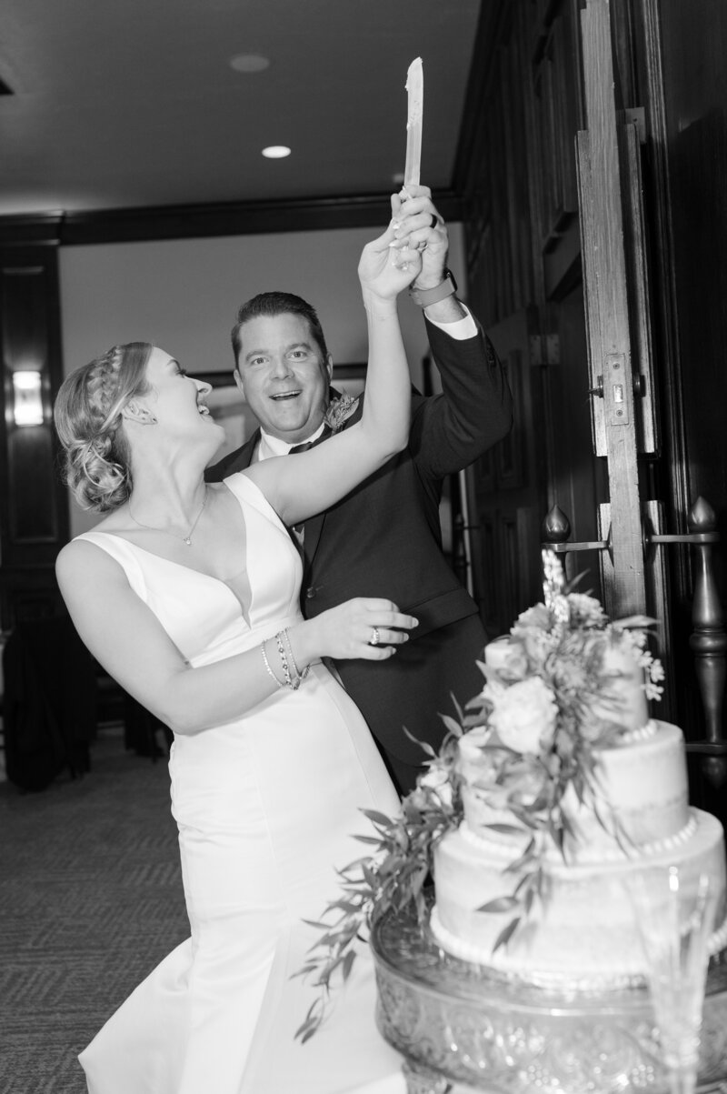 A couple laughs at each other as they cut the cake at their wedding reception.