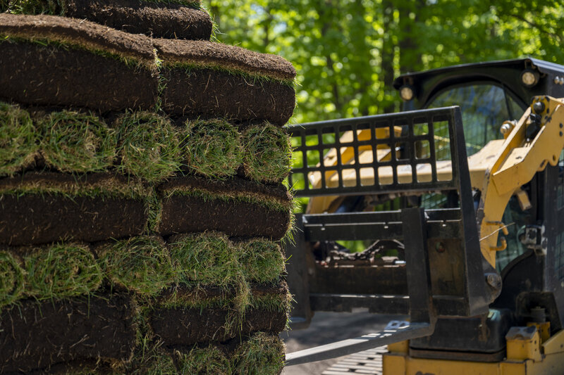 Skid loader lifting a pallet of sod 