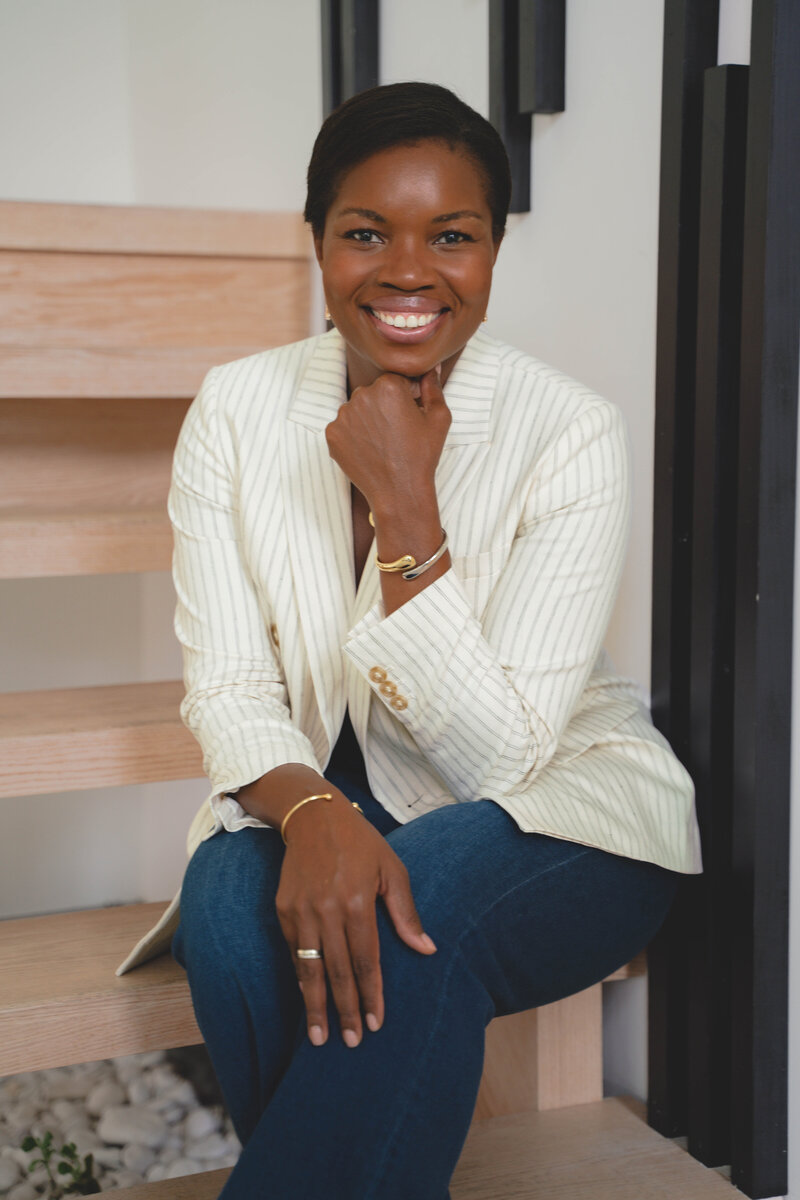 Black professional career coach wearing blue blazer and white shirt at desk with Apple computer.