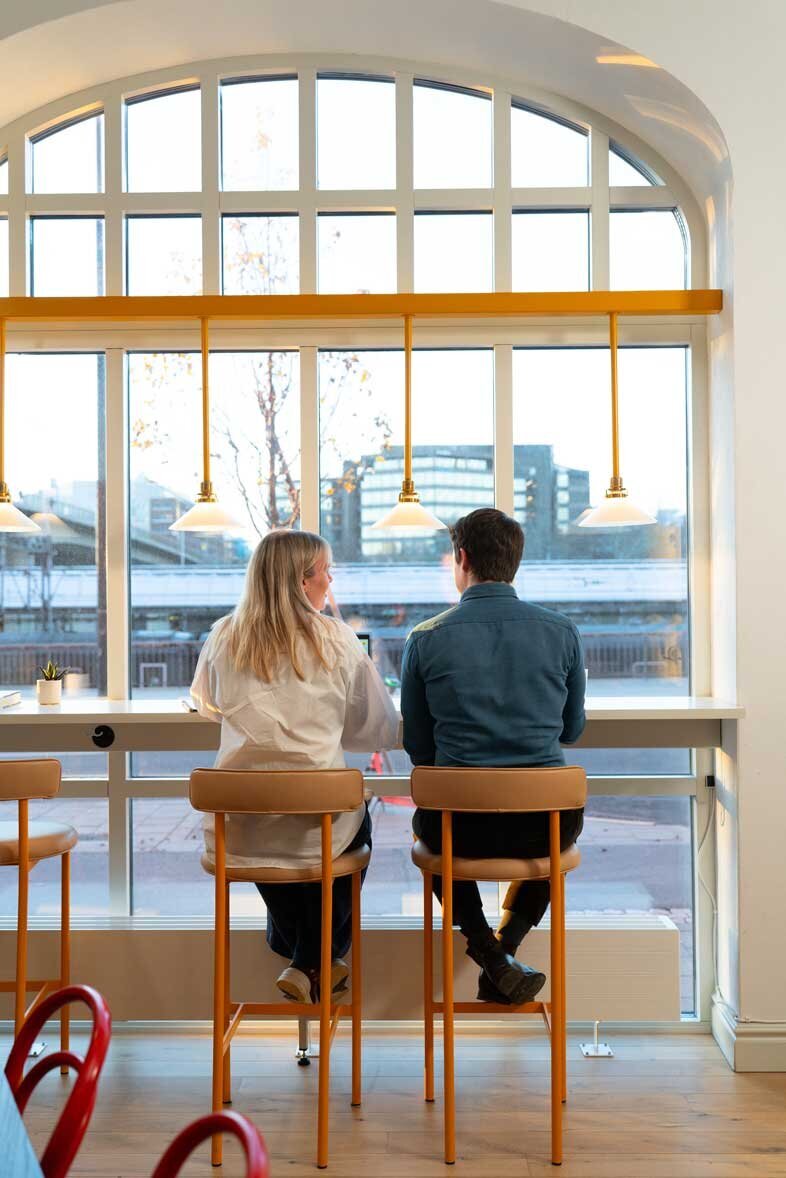 två-personer-sitter-vid-fönster-på-stolar