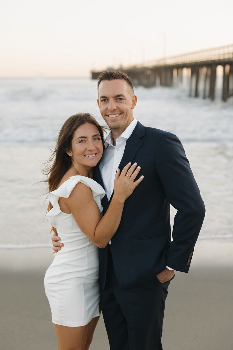 a couple taking their engagement pictures at shell beach sitting in the water with playful photography