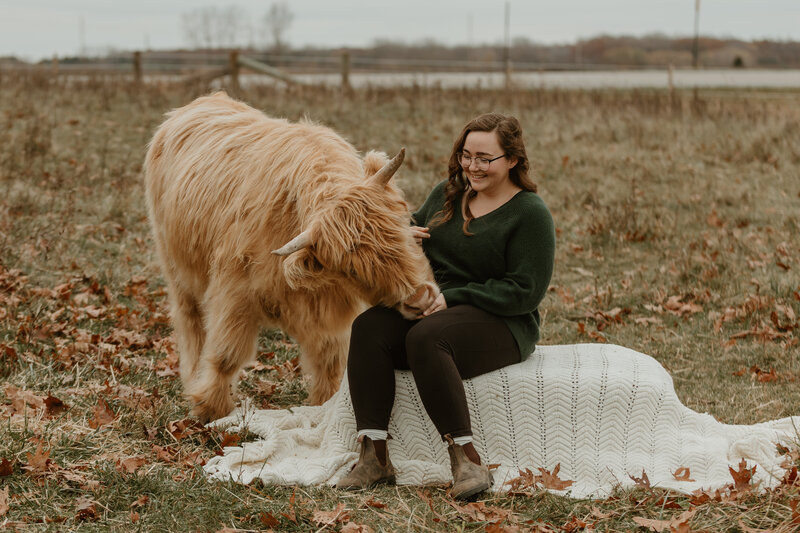 photo of woman sitting next to cow