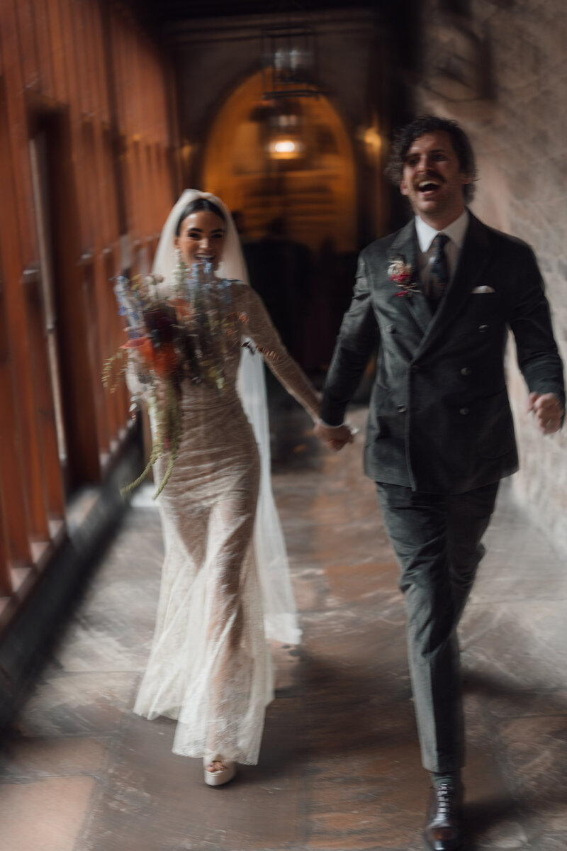 couple walk the halls hand in hand creating motion blur in at the intimate ceremony held in st etheldreda's chuch in central london