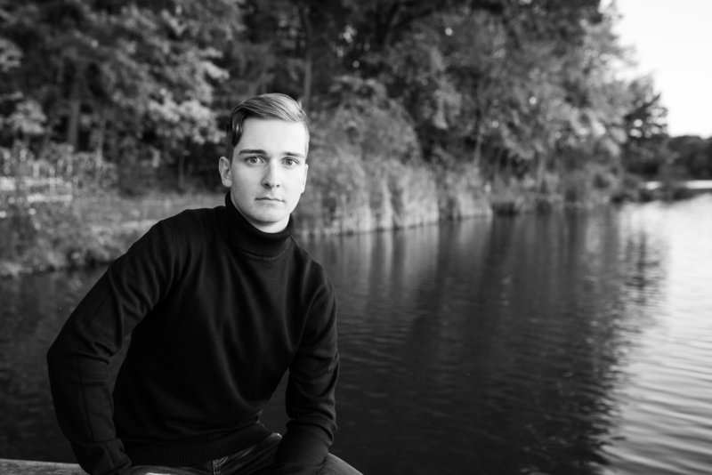 sippo lake senior session, black and white photo, senior is sitting on a bench by the water, photographed by Jamie Lynette Photography Canton Ohio Senior Photographer