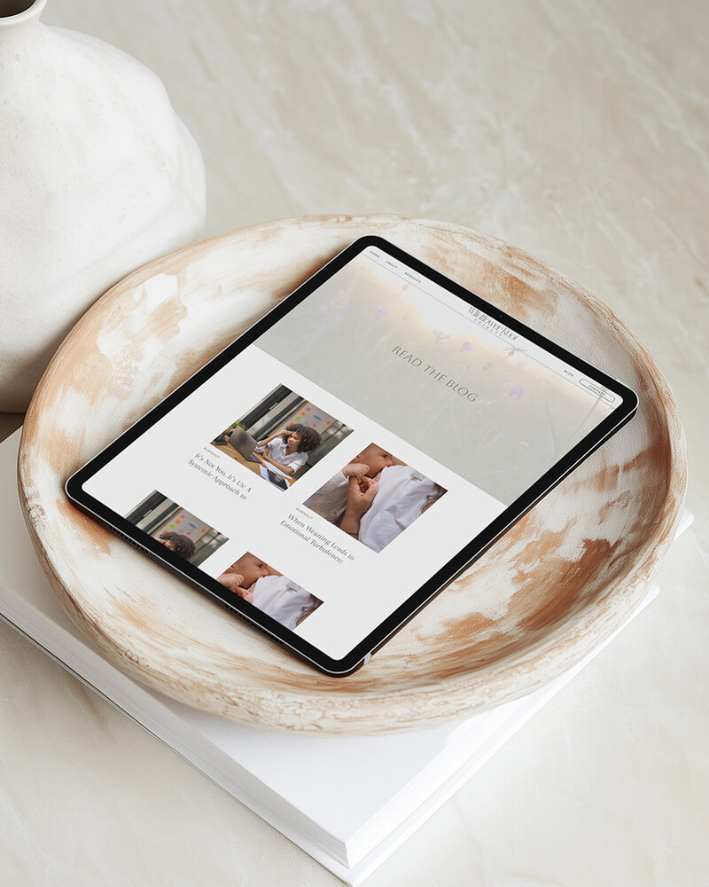 iPad on a wooden plate beside a vase and a book, creating a cozy scene for a therapist blog.