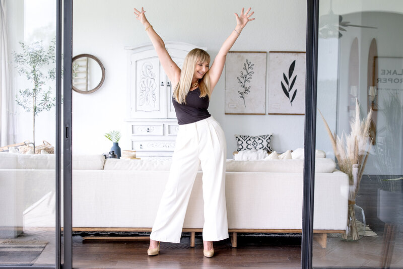 woman in a living room with her arms in the air and smiling for her brand photo captured by Orlando photographer