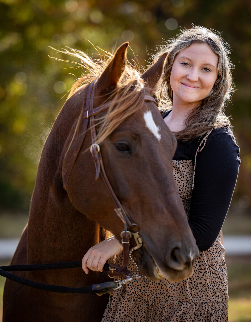 Girl Next to brown horse smiling
