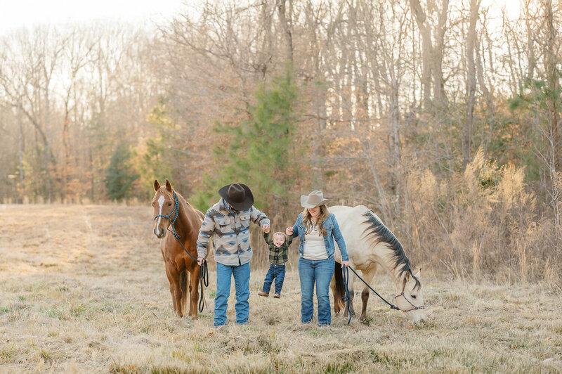 family of five in light colors walking hand in hand on a horse farm