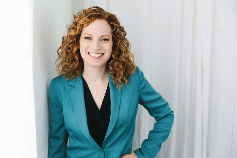 Red haired woman wearing blue blazer smiling at viewer