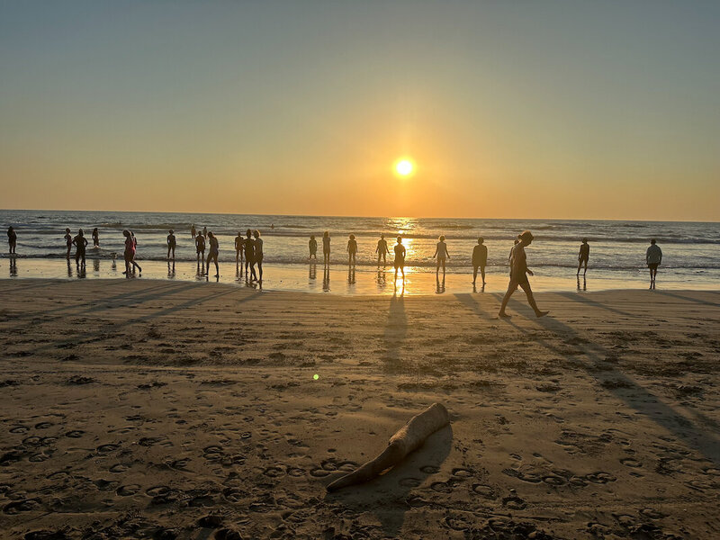 sunset at beach with ground of people walking diana hill wise effort retreat yoga blue spirit costa rica