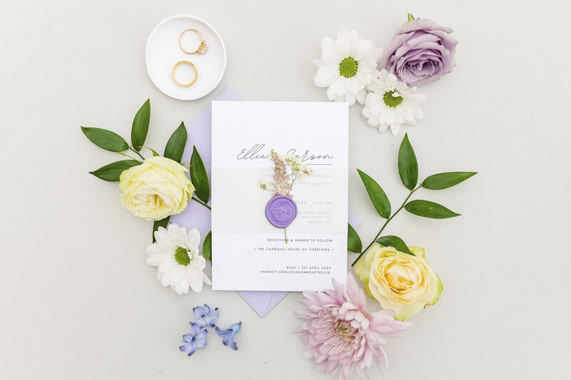 white wedding invitation surrounded by colorful flowers