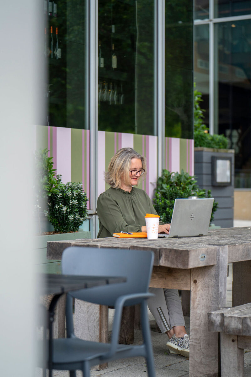 corporate photography of a lady on a laptop working outside