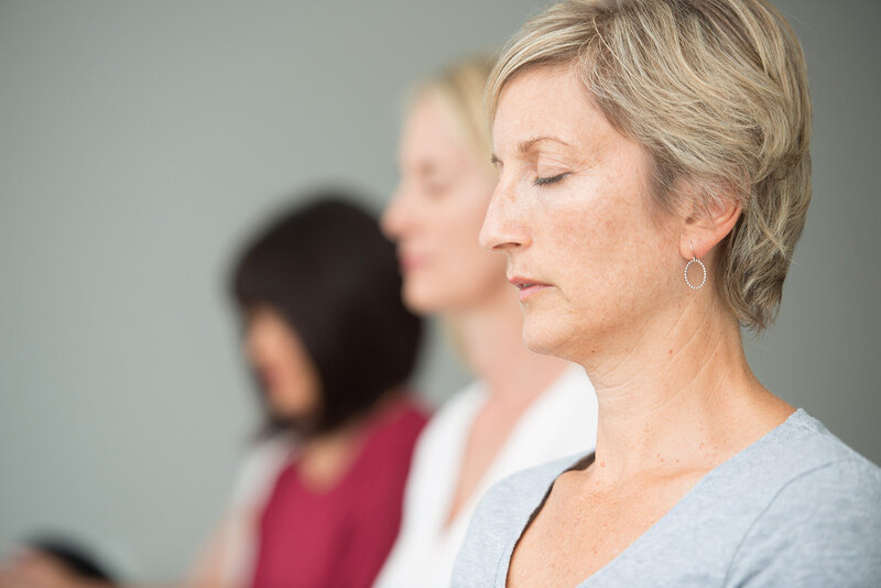 Three women in a Yoga of Stillness session with eyes closed
