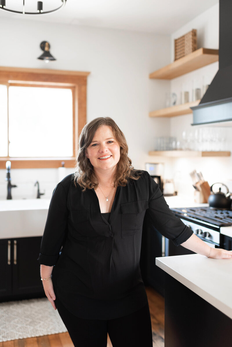 Realtor, Lindsey Drewes, smile for photo in black blouse in kitchen