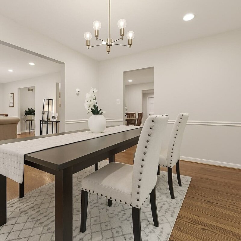 Bright dining room with modern chandelier, upholstered chairs, and dark wood table.