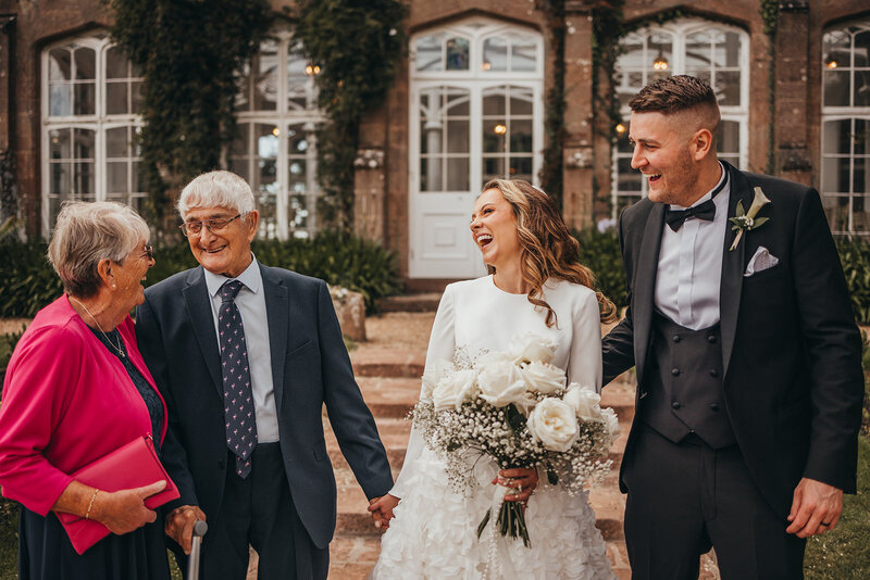 bride and groom pose with grandparents 
