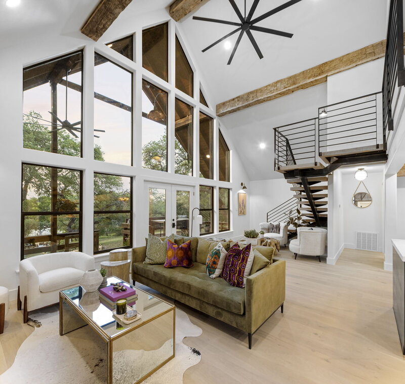 High vaulted ceiling living room with large bay windows looking out to nature