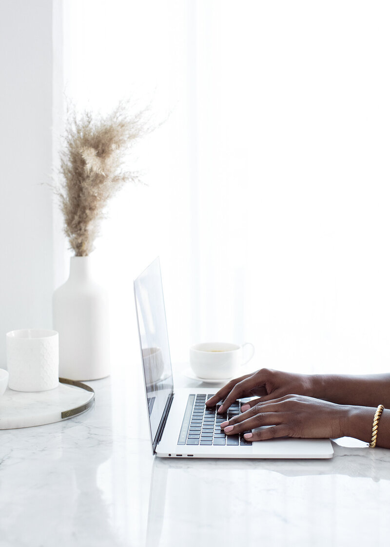 Woman's hands with pink nails typing on a laptop