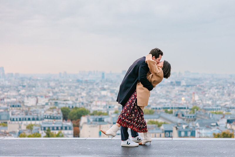 “Man and woman holding hands during a Paris proposal at the Louvre and Tuileries Garden — the man smiling as the woman looks on in excitement.