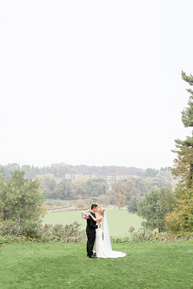 Bride and Groom walk across bridge holding hands at Lionhead Golf and Country Club Wedding Venue in Oakville Ontario