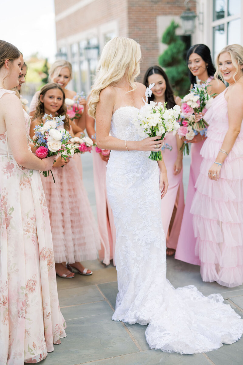 Bride standing in front of her bridesmaids in pink dresses