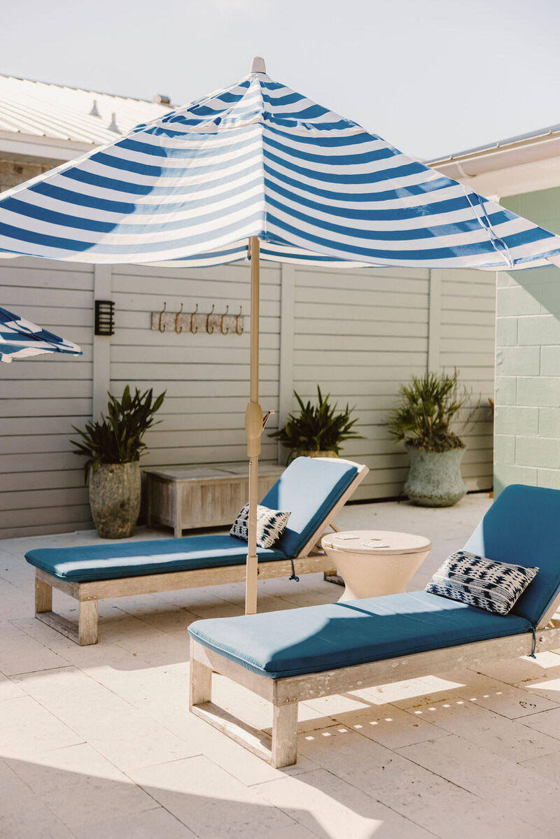 pool loungers with striped umbrella