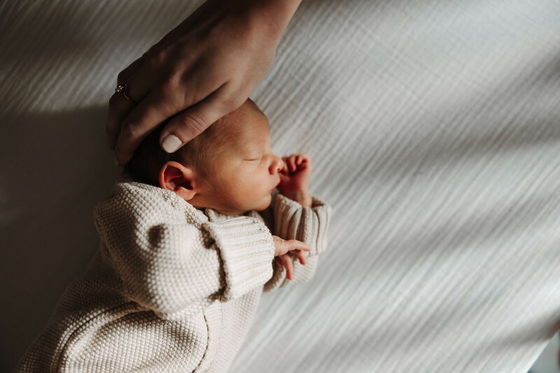 Mother gently caresses newborn baby's head
