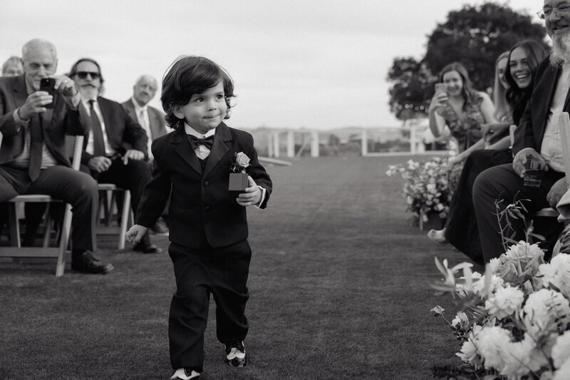 A young ring bearer confidently walking down the aisle, captured by T & M Photography (TM Picture), highlighting in the moment photography and lifestyle coverage for weddings in Sacramento CA.