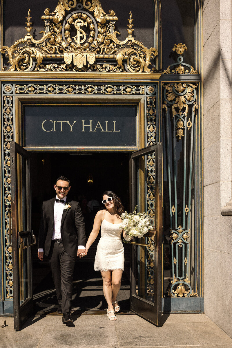 San Francisco couple walk out door after SF City  Hall Wedding