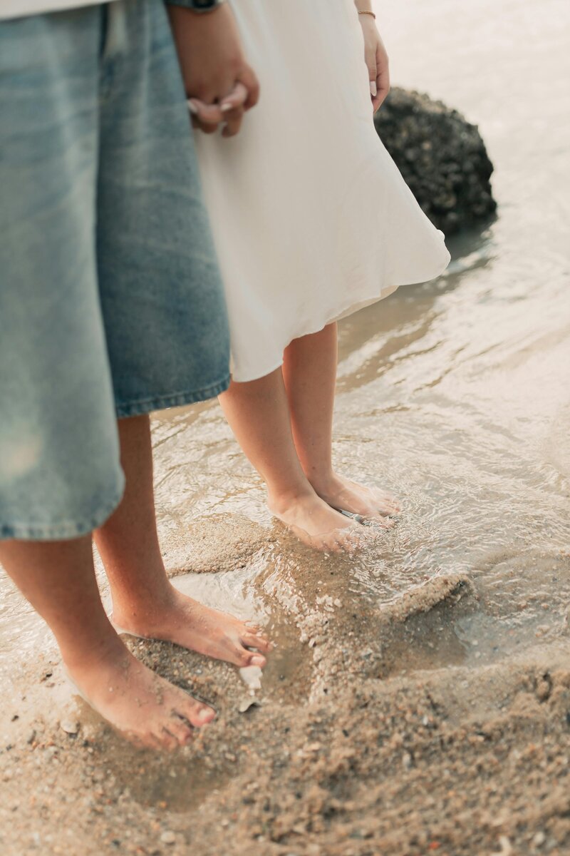 two people holding hands on the beach, showing supportive vibes only