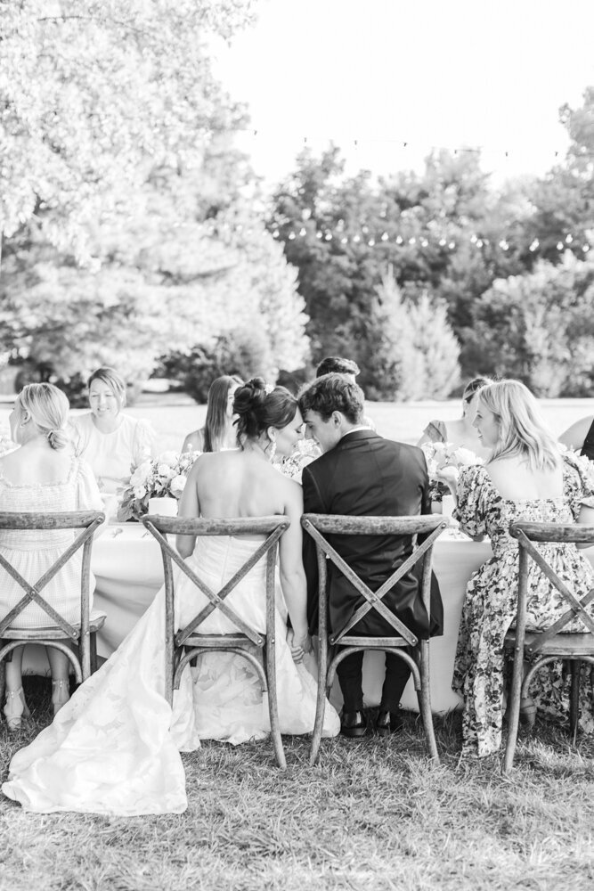 bride and groom touching foreheads while sitting at wedding reception table