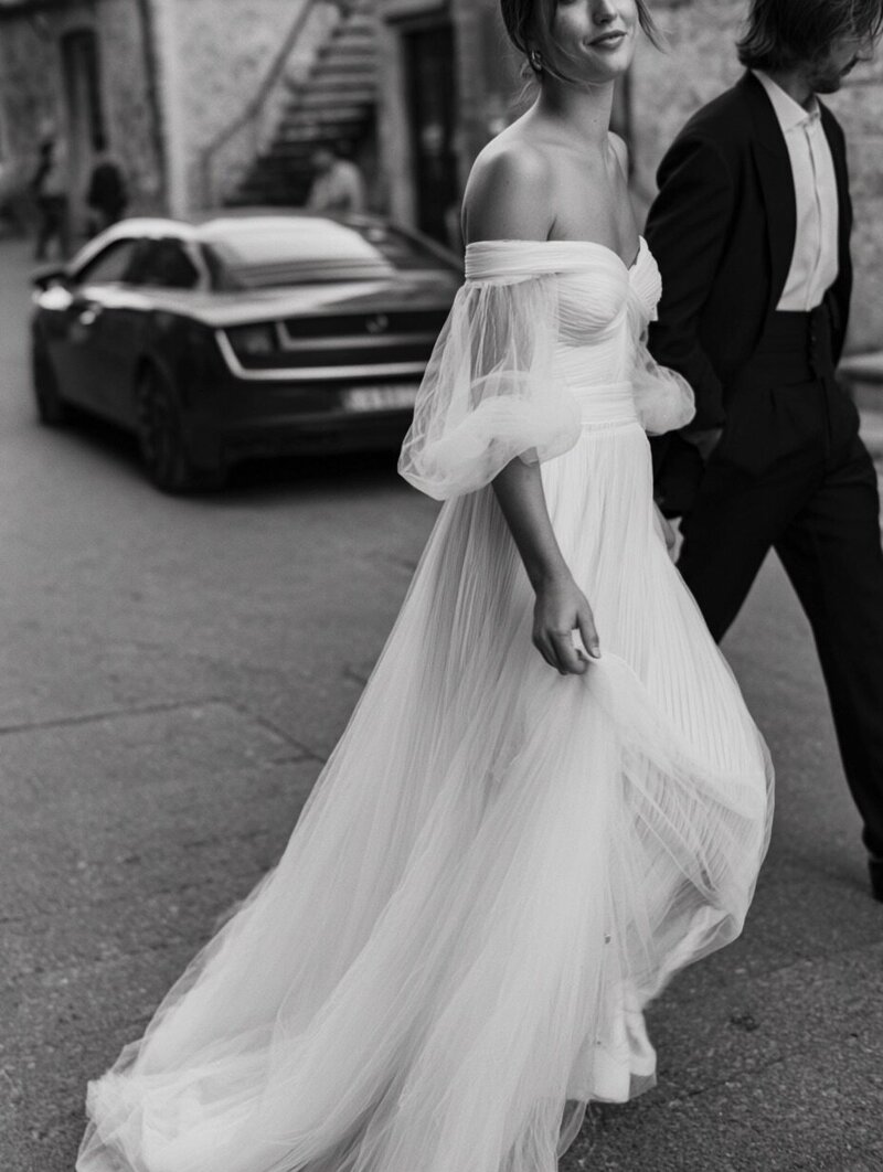 Black and white editorial wedding photo of a stylish bride and groom walking together, used by Barilliant to inspire modern luxury wedding gifting and personalised chocolate bar design.