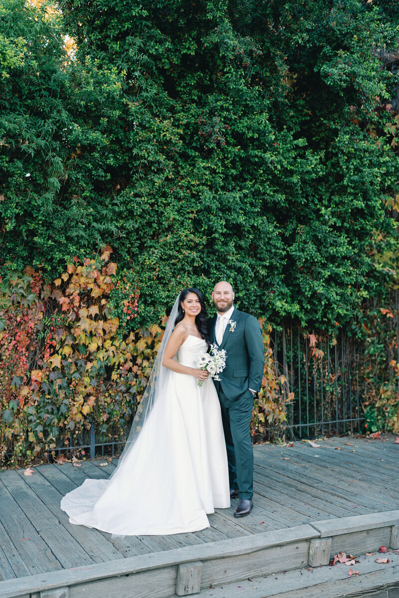 bride and groom pose for a classic wedding portrait after their ceremony against a beautiful fall time background