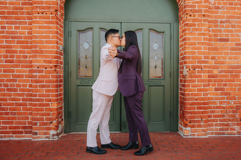 A couple leans in for a kiss while holding hands