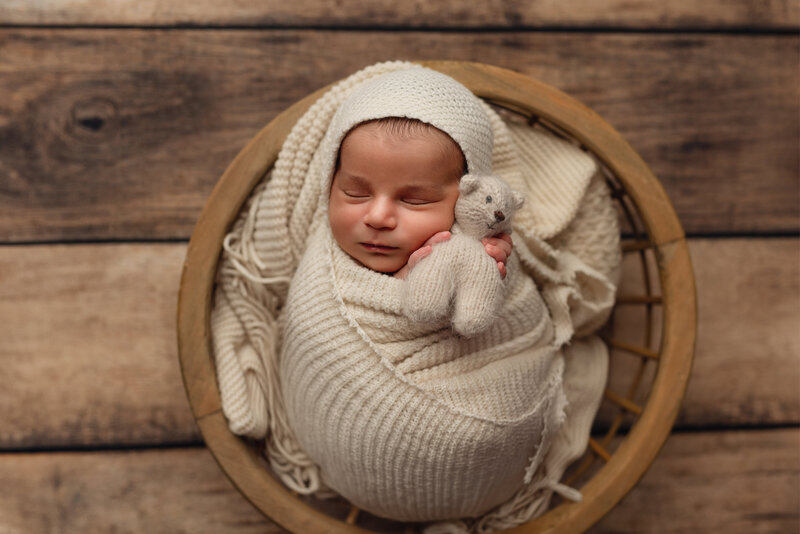 Neutral, cozy newborn portrait with cream wraps and handmade teddy.