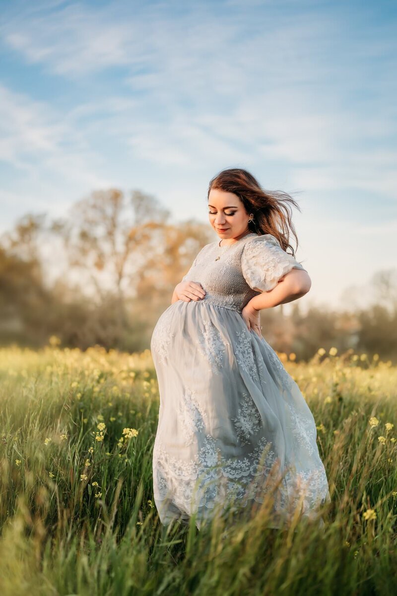 pregnant mama wearing a blue maternity dress in a spring photo session