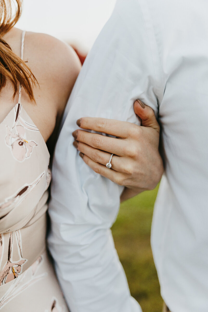 Close up image of a girl's hand around a guy's arm showing her wedding ring