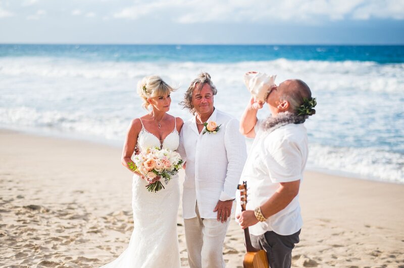 man blows shell conch at beach elopement in Maui