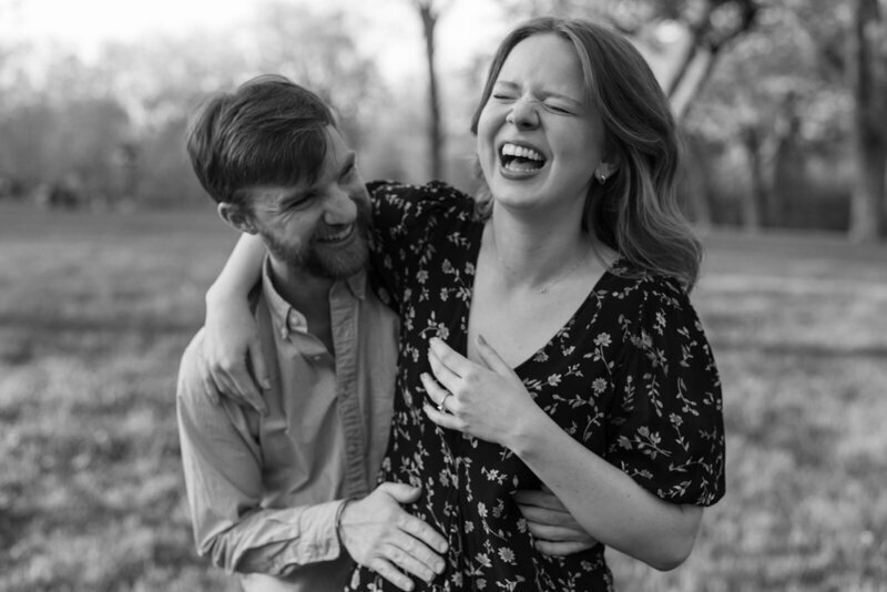 black and white photo by minnesota engagement photographer tom thornton of couple laughing together outside in open field 