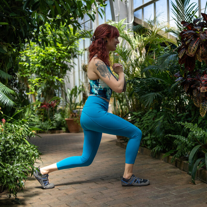 a woman in blue workout clothes does a bodyweight lateral lunge