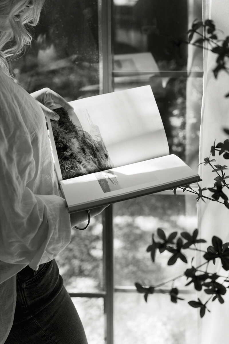 Black and white image of a woman flipping though a photo book