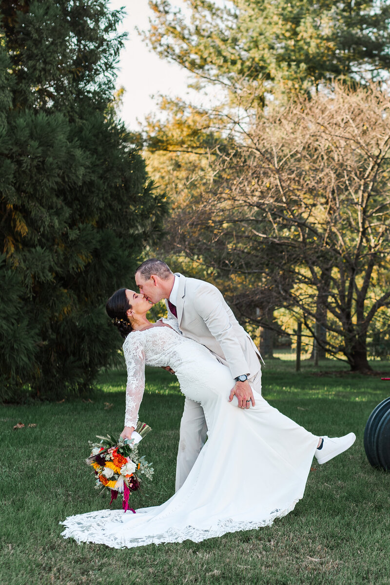 A groom dipping a bride as they kiss.